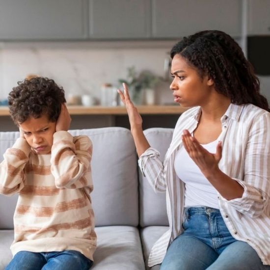 mãe repreendendo seu filho e ele com as mãos no ouvido não querendo escutar
