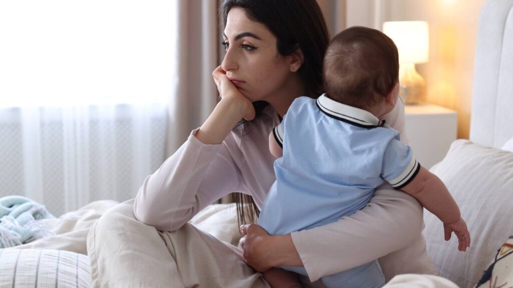 mulher pensativa e segurando seu bebê enquanto ela se arrepende de ter virado mãe