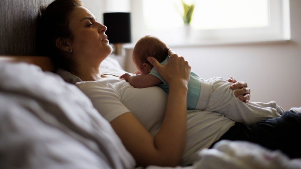 mãe deitada na cama e com o seu bebê sob a barriga