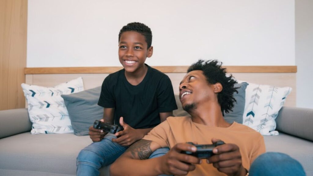 pai sendo um bom educador parental com o seu filho enquanto joga video-game na sala e estão segurando os controles